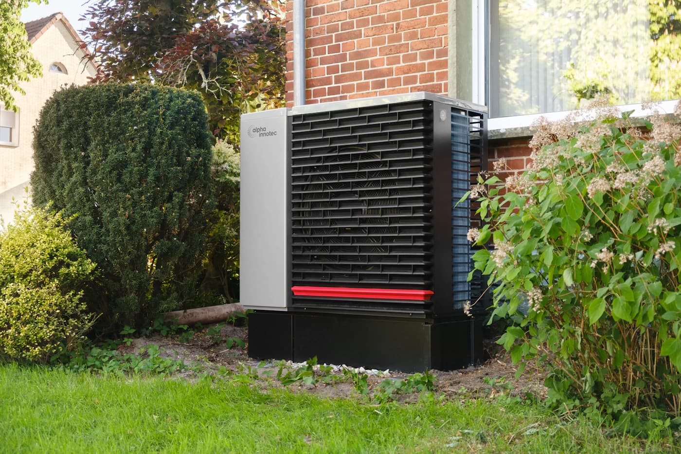 Buitenunit van een warmtepomp naast de gevel van een woning